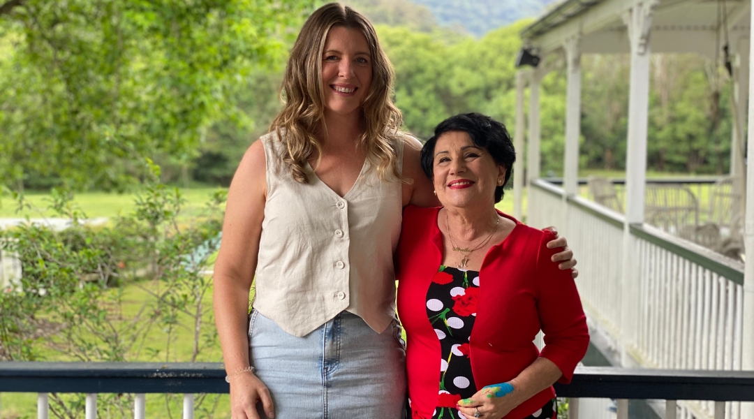 one older woman and one younger woman standing on a verandah in the country